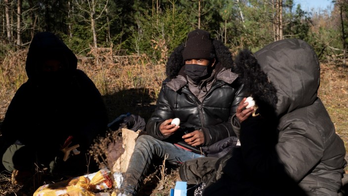 Migrants from Somalia eat after crossing the Belarusian-Polish border in Siemianowka