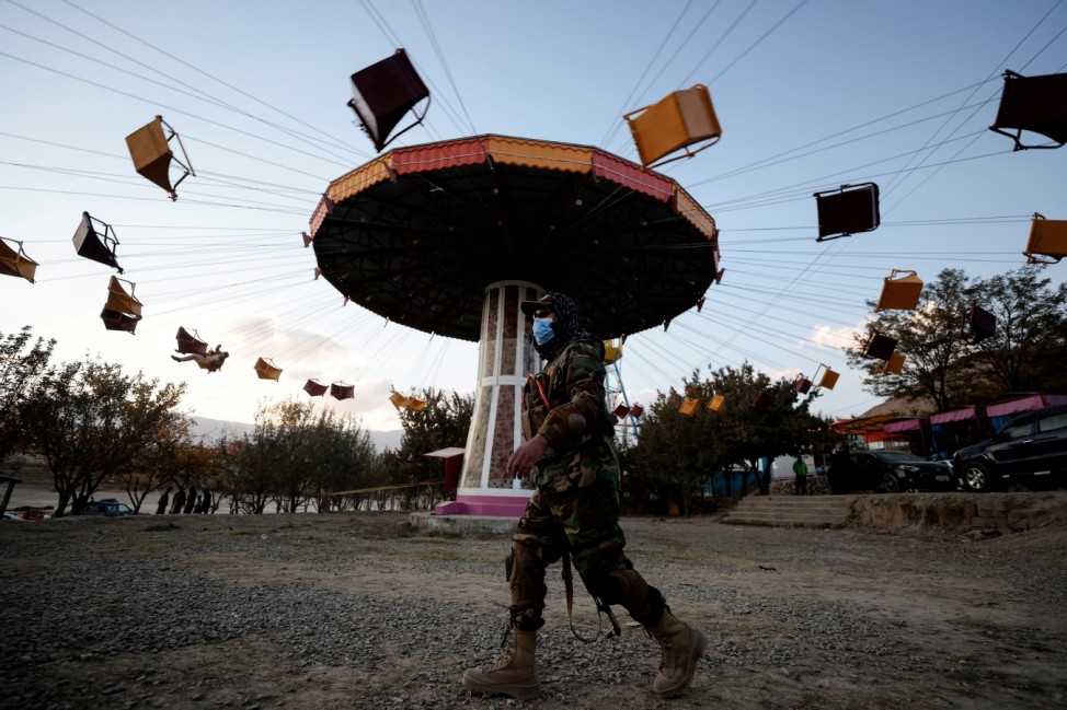 A Taliban fighter walks past a ride as he takes a day off to visit the amusement park at Kabul's Qargha reservoir in the outskirts of Kabul