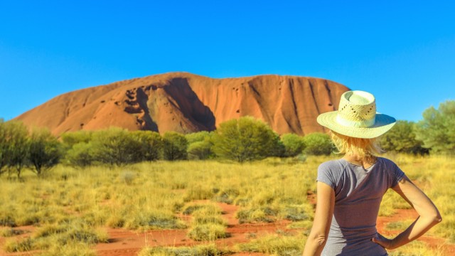 Tourist woman in hat looks at Uluru (Ayers Rock) in the dry season, Uluru-Kata Tjuta National Park, UNESCO World Heritag