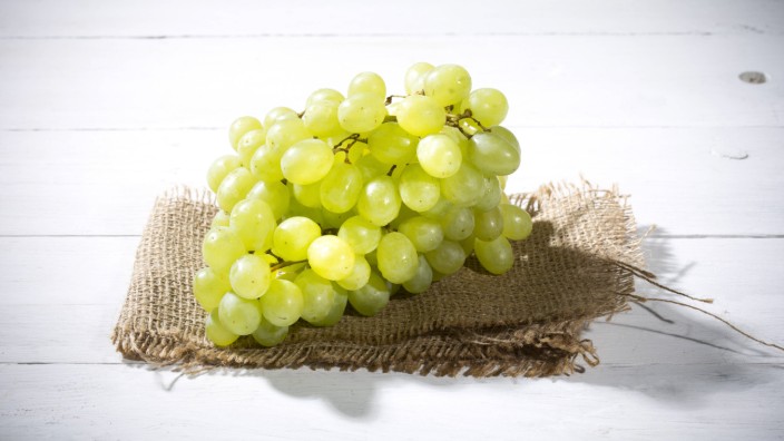 Seedless white grapes on jute and white wooden table PUBLICATIONxINxGERxSUIxAUTxHUNxONLY MAEF007865