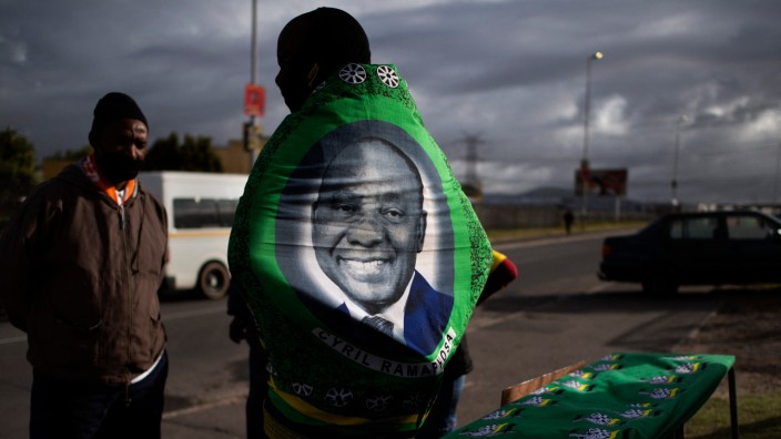 Südafrika: Die Wähler sind dem ANC in Scharen davon gelaufen und die Wahlbeteiligung ist gesunken: Mann mit einem Tuch, das Staatspräsident und ANC-Chef Cyril Ramaphosa zeigt, vor einem Wahllokal in Langa bei Kapstadt.