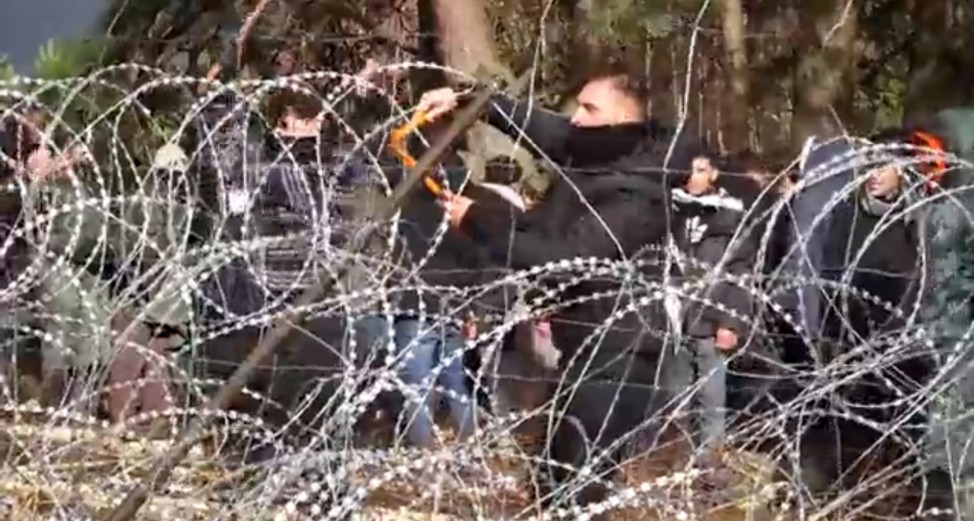 Migrants use wire cutters to cut the barbed wire as they try to cross the Belarus/Poland border near Kuznica Bialostocka