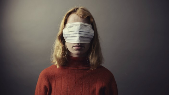 Teenage girl wearing protective face mask on eyes while standing against gray background model released Symbolfoto JATF0