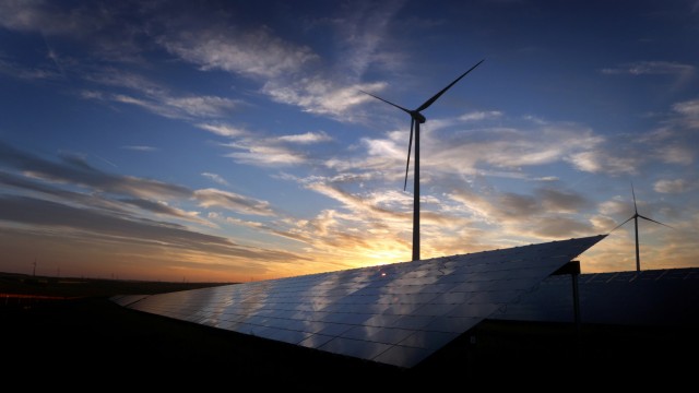 Wind- und Solarstromanlagen: Windräder hinter den Solarzellen einer Solarkraftanlage. Künftig will das Unternehmen die gesamte Lieferkette präziser zurückverfolgen und prüfen.