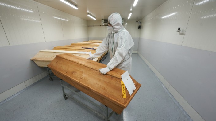 Corona: Alltag in der Seuche: Ein Mitarbeiter des Krematoriums in Dachsenhausen bereitet in Schutzkleidung einen Sarg auf die Einäscherung vor.
