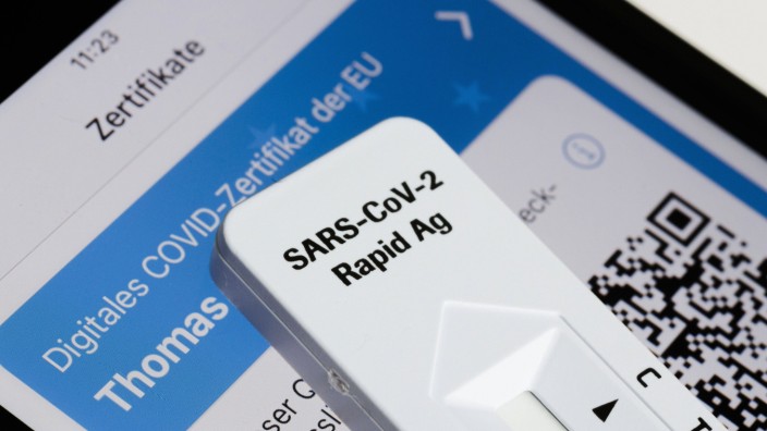 Ein negativer SARS-CoV-2 Rapid Ag Antigen Schnelltest liegt einem Smartphone, welches ein digitales COVID-Zertifikat de