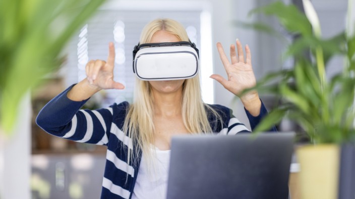 Mature businesswoman gesturing while wearing virtual reality headset at home office