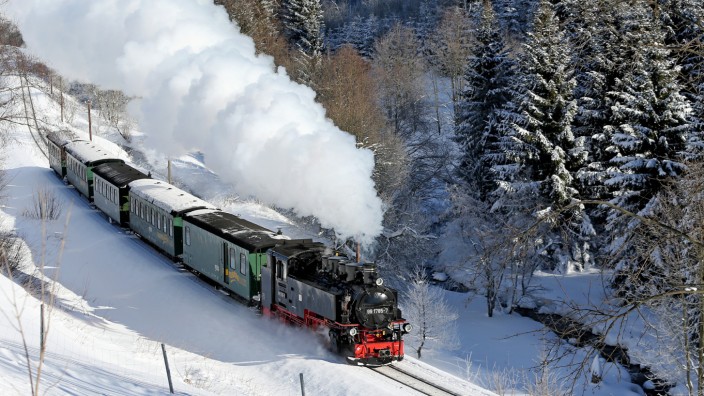 Geschichte der Eisenbahn: Ein Zug der Fichtelbergbahn dampft durch das verschneite Erzgebirge bei Oberwiesenthal (Sachsen). Die 1897 eröffnete Schmalspurbahn verbindet auf ihrer 17,4 Kilometer langen Strecke die Orte Cranzahl und Oberwiesenthal.