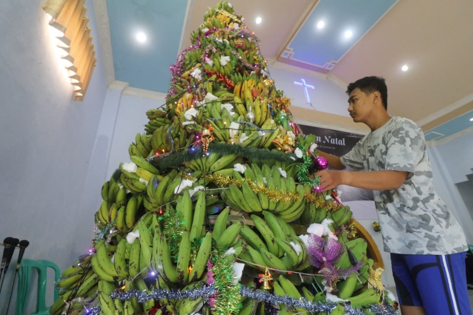 A man arranges Christmas tree from bananas at a church ahead of the Christmas mass in Kediri