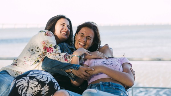 Mother and daughter laughing while embracing against sea model released Symbolfoto DCRF00302