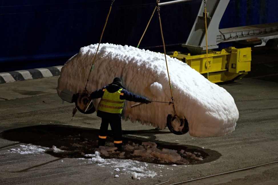 A worker unloads an ice-covered vehicle from the cargo ship Sun Rio in the port of Vladivostok