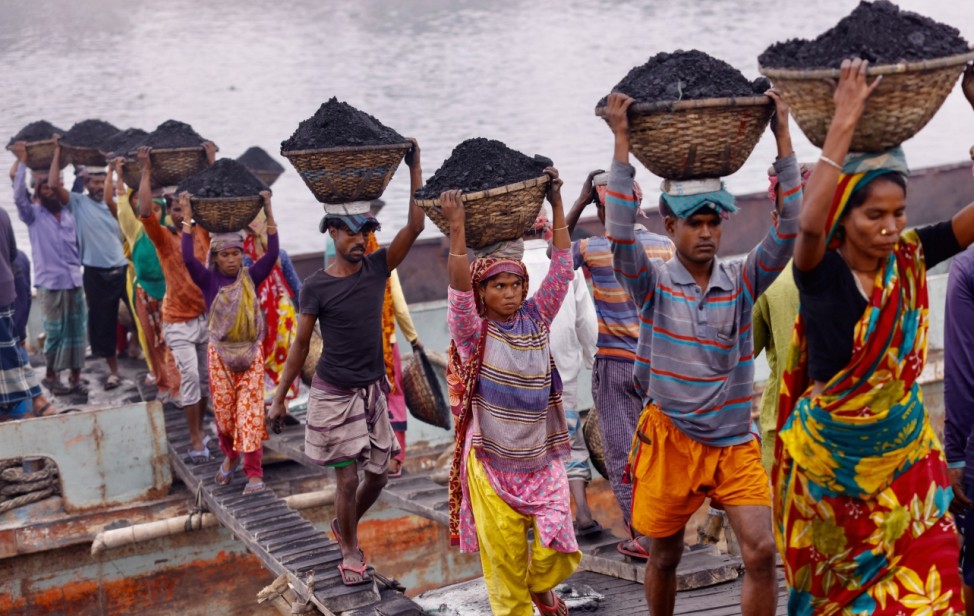 Workers carry coal as they unload a ferry at Gabtoli in Dhaka