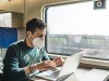 Man with covid-19 protective mask working with laptop while traveling by train; Masken, FFP2, Corona
