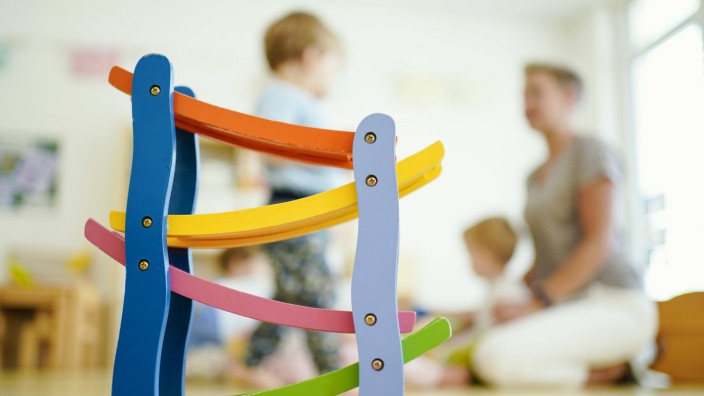 Kinderbetreuung: Gesuchte Fachkraft: Eine Erzieherin spielt in einer Kindertagesstätte hinter einer Rollbahn mit Kindern.