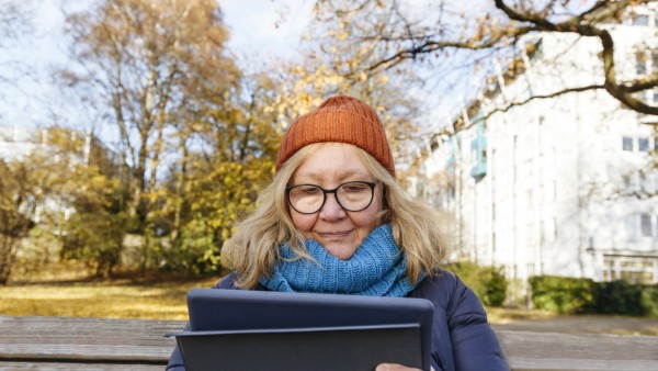 Senior woman using tablet PC sitting on bench in park model released, IHF00731