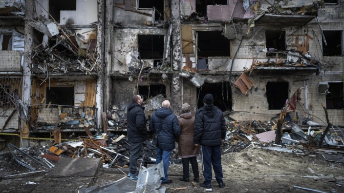 Krieg in der Ukraine: Menschen vor einem zerstörten Wohnhaus