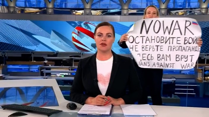 Pressefreiheit: Wegen dieser Aktion fürchtet Marina Owssjannikowa (hinter dem Plakat) jetzt um ihre Sicherheit.