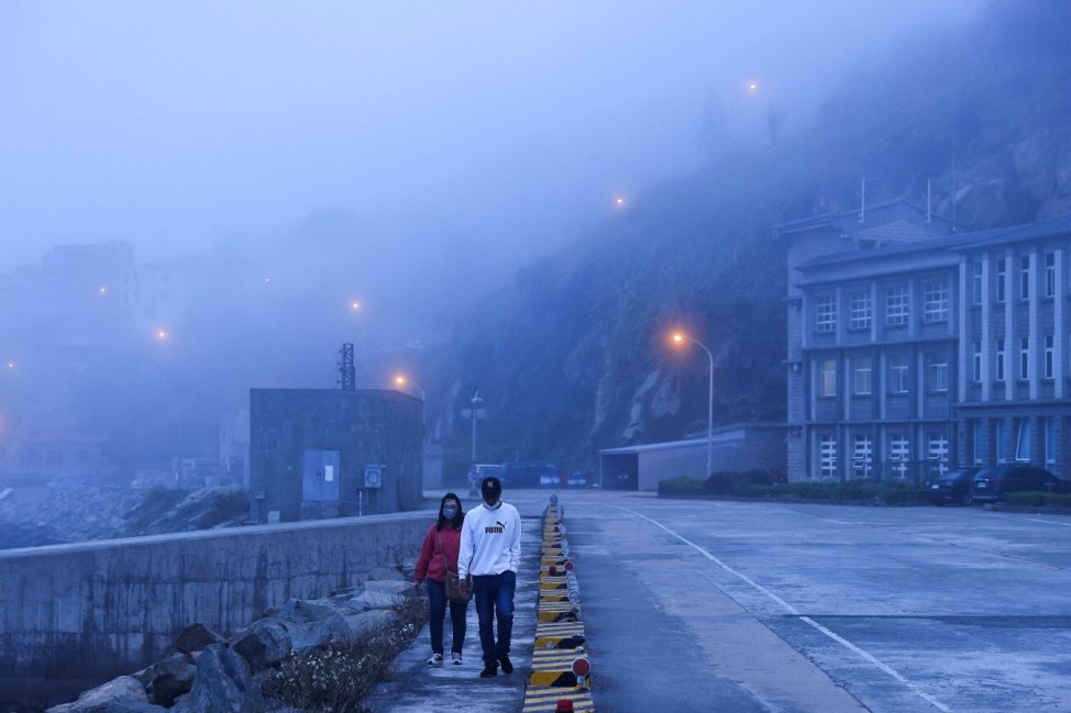 A couple walks in the early morning fog in Dongyin