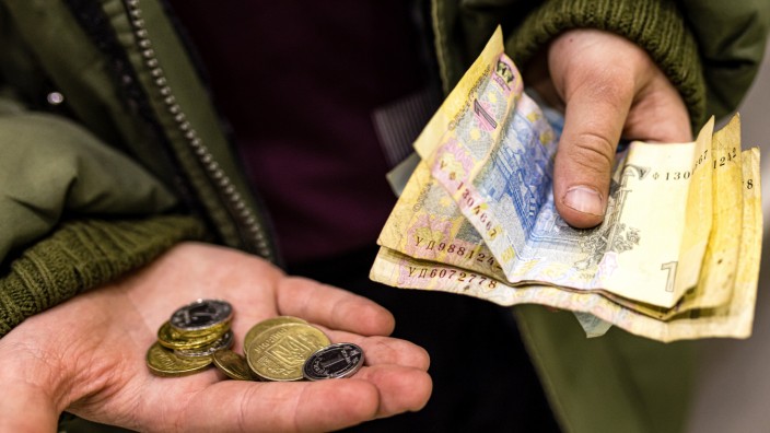 Währung: Ein Junge hält ukrainische Münzen und Geldscheine in seinen Händen.