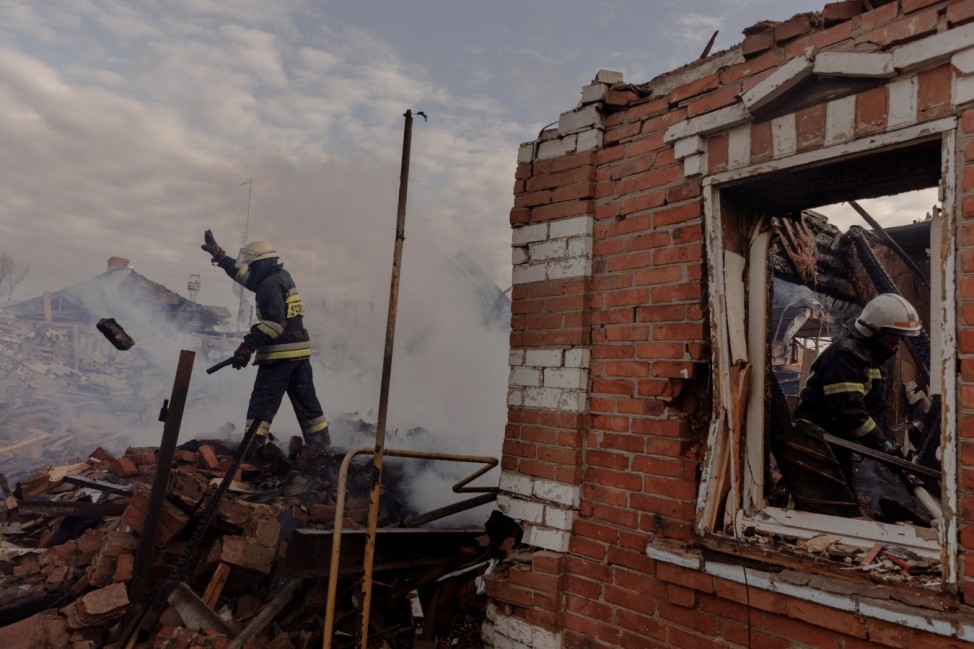 Firefighters work amid the debris of residential houses that were destroyed during shelling in a settlement outside Kharkiv as Russia's attack on Ukraine continues