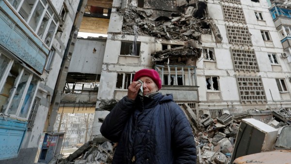 A local resident reacts next to the building where her destroyed apartment is located in the besieged city of Mariupol