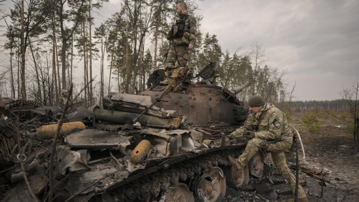 Konfliktforschung: In der Nähe von Kiew: Ukrainische Soldaten am Donnerstag an einem zerstörten russischen Panzer.