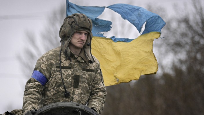 Ukraine: Ein ukrainischer Soldat steht mit der Flagge seines Landes im Hintergrund auf einem Panzer, außerhalb von Kiew.