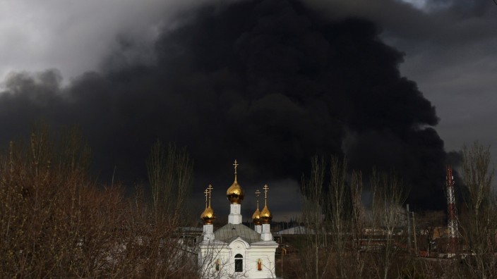 Ukraine: Eine orthodoxe Kirche in Odessa, bedrohlich umwölkt von Schwaden, die aus einer Raffinerie aufsteigen, die zuvor von russischen Raketen getroffen wurde.