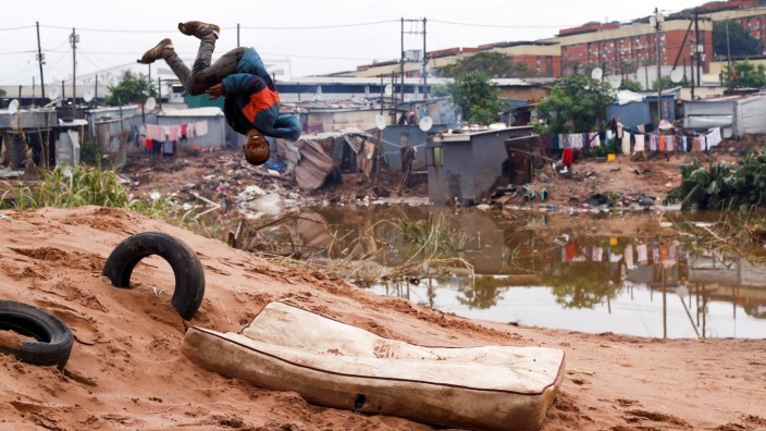 A child does a back flip onto an old mattress among the destruction caused by flooding in Umlazi near Durban