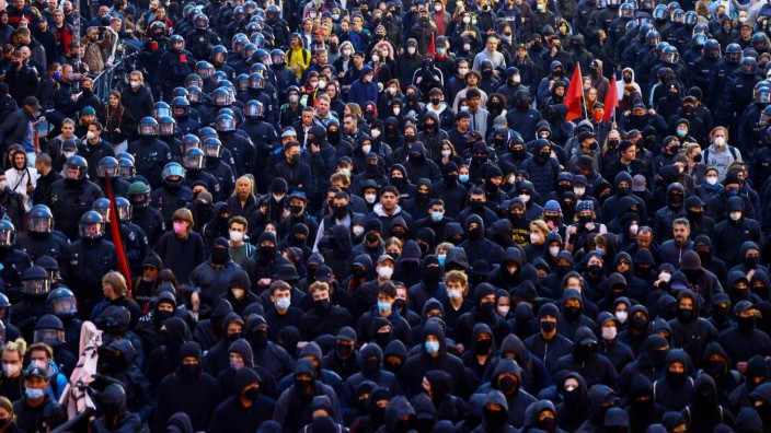 Tag der Arbeit: Polizisten laufen am 1. Mai in Berlin neben schwarz gekleideten Demonstranten.