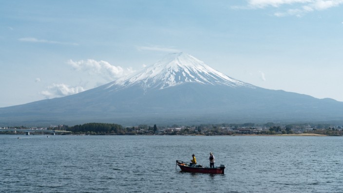Japan: Japan, Yamanashi: Fischer angeln in einem Boot auf dem Kawaguchi-See vor dem Vulkan Fuji.