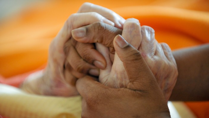 Pflegeausbildung: Eine Auszubildende hält die Hand einer Seniorin in einem Altenwohnheim in München.