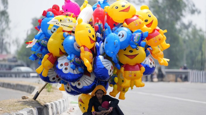 Klimakolumne: Indien, Jammu: Eine Ballonverkäuferin wartet in der Hitze auf Kundschaft.