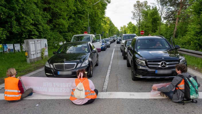 Klimawandel: Protest am Ende der Autobahnabfahrt in Fürstenried: Zwei Männer und eine Frau blockieren die vielbefahrene Straße und fordern mit Plakaten eine klimafreundlichere Politik.