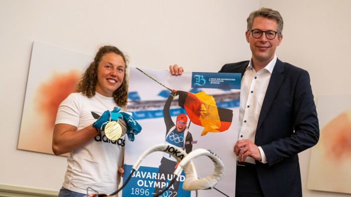 Sportgeschichte: Ex-Biathletin Laura Dahlmeier übergibt an Wissenschaftsminister Markus Blume Erinnerungsstücke, etwa ihre Goldmedaille von 2018, für das Haus der Bayerischen Geschichte.