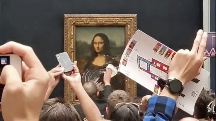 Kunst: Nach dem Attentat auf die Mona Lisa wischt ein Museumsmitarbeiter die Sahne vom Schutzglas.