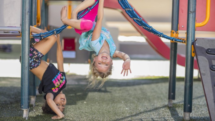 Familientrio: Zwei Mädchen klettern am Spielgerät in einer Kindertagesstätte.