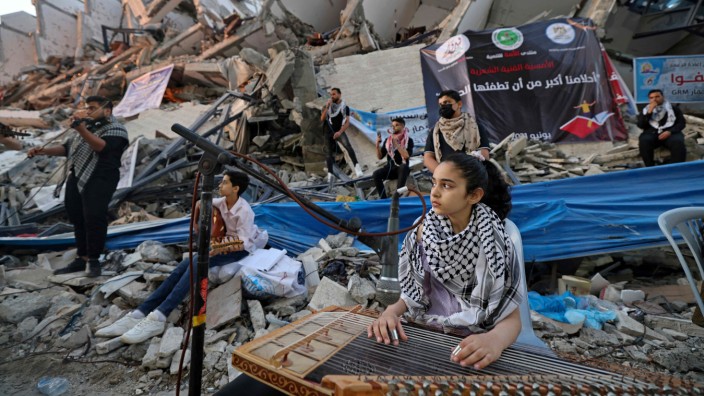 Nahost: Eine junge Musikerin sitzt im Juni 2021 in den Trümmern des Hanadi Tower in Gaza-Stadt. Erst eine gute Woche zuvor war der elftägige Krieg zwischen der Hamas und Israel zu Ende gegangen.