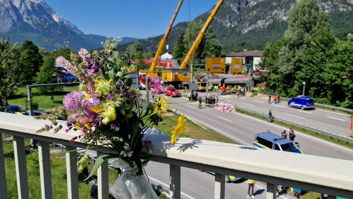 Nach dem Unfall: Trauer am Tag danach: An einem Brückengeländer hat jemand Blumen befestigt, im Hintergrund die Unglücksstelle in Burgrain.