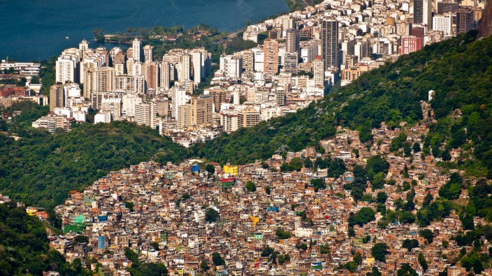 Oded Galor: "Die Reise der Menschheit durch die Jahrtausende": Fanal für die ewige Armut und Ungleichheit oder bloß bedauerliches Übergangsphänomen? Blick auf die Favela da Rocinha, den größten Slum Brasiliens, im Hintergrund die Skyline von Rio de Janeiro.