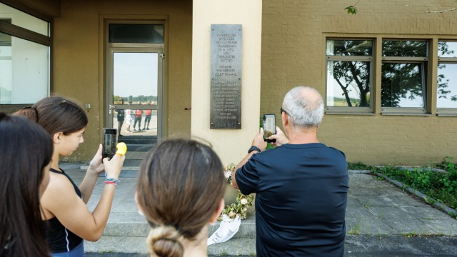 Olympia-Attentat 1972: Fotos machen die Teilnehmer der Führung im Fliegerhorst an der Stelle, an der eine Tafel an den dort erschossenen Polizeibeamten Anton Fliegerbauer erinnert.
