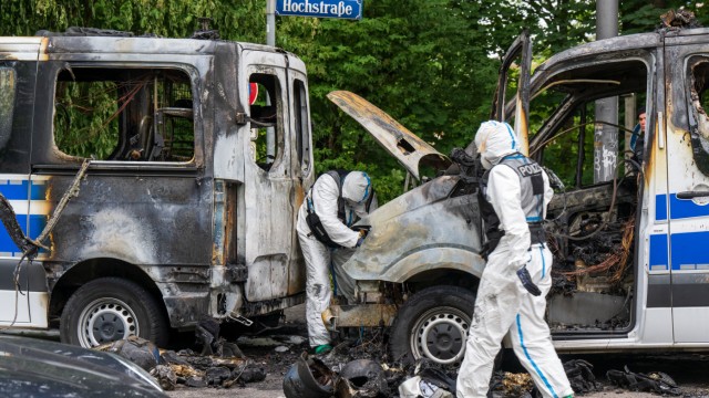 Newsblog zum G-7-Gipfel: Ermittler der Spurensicherung arbeiten an einem Polizeiauto, das in der Nacht ausgebrannt ist.