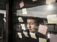 Tired woman leaning against window pane with sticky notes model released Symbolfoto property releas