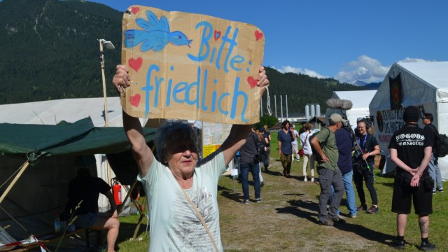 Protestcamp zum G-7-Gipfel: Es ist eine bunte Mischung Menschen, die gegen den G-7-Gipfel in Elmau protestieren: Hier eine ältere Frau, die ein Transparent mit der Aufschrift "Bitte friedlich" hoch hält.
