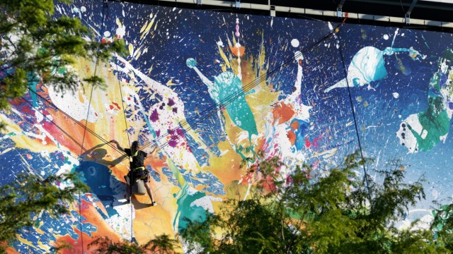 Kolumne "Das ist schön": Der Maler Christian Awe, hoch über der Straße angeseilt, an einer Hausfassade.