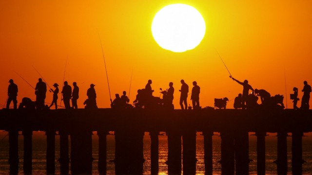 People fish from a pier during sunset in the settlement of Novofedorivka