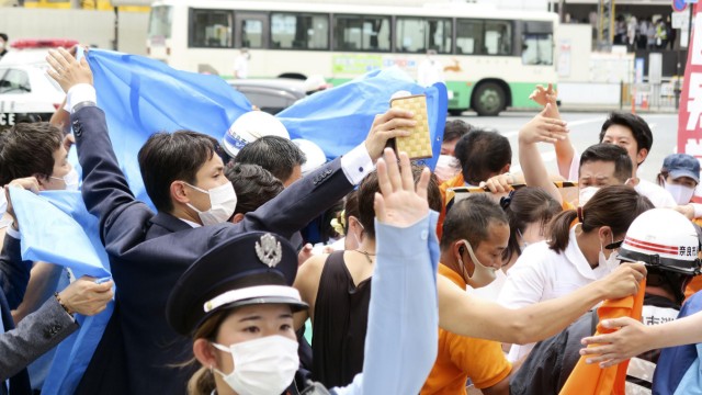 Japan: Nach Schüssen auf Japans Ex-Premier Shinzō Abe halten Menschen einen Sichtschutz hoch.