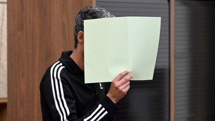 Säure-Attentat auf Manager: Der Angeklagte hält sich bei Prozessbeginn Ende Juni im Gerichtssaal in Wuppertal eine Mappe vor das Gesicht.