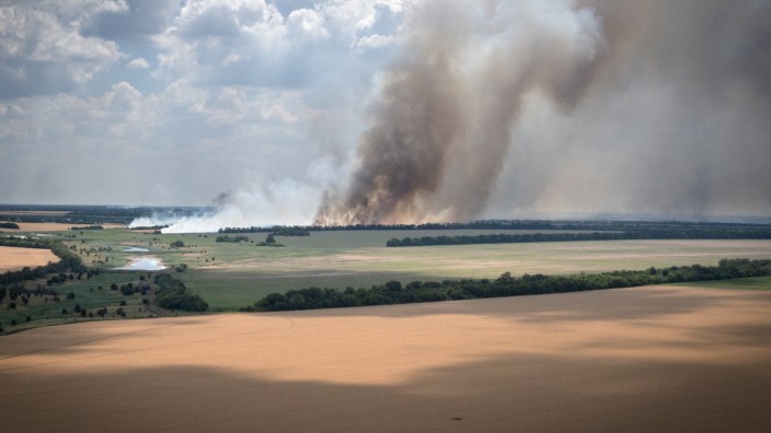 Ukraine: Feuer und Rauch an der Front in der Region Dnipropetrowsk, davor ein Getreidefeld. Nicht selten verbrennen Felder infolge der Kämpfe.