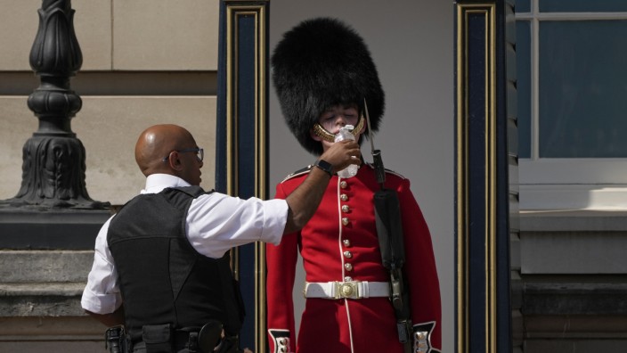 Hitzewelle in Großbritannien: Stay hydrated! Ein britischer Polizist versorgt vor dem Buckingham Palace einen Soldaten mit Wasser.